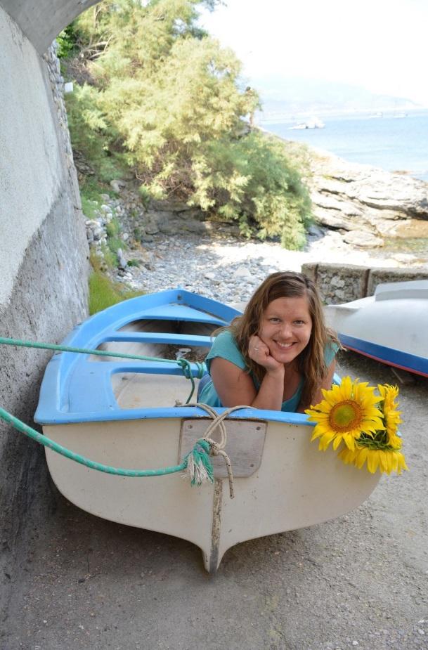 Meitene guļ laivā, blakus saulespuķes