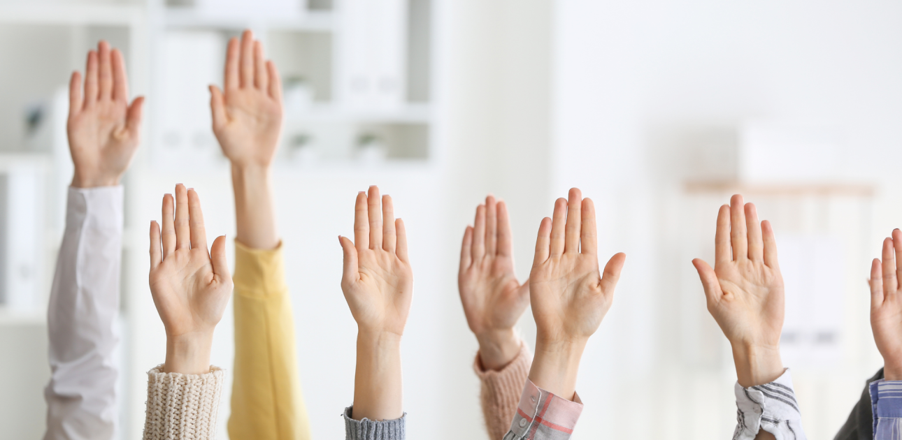 vairāku cilvēku rokas paceltas gaisā, fonā biroja telpas