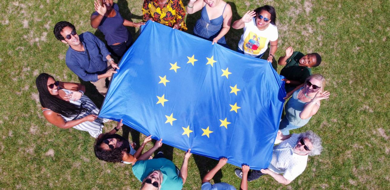 Attēlā redzama jauniešu grupa, kas tur Eiropas Savienības karogu