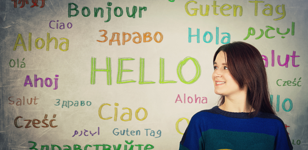 Meitene pie plakāta, uz kura uzrakstīti vārdi dažādās valodās