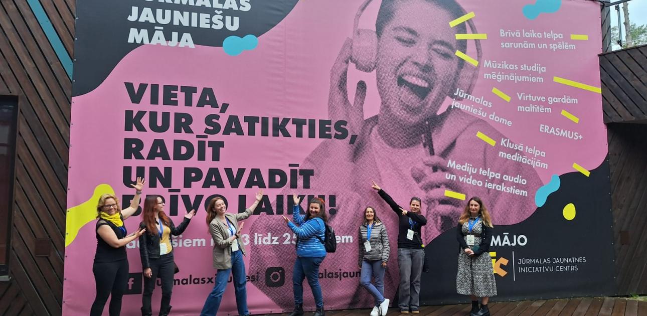 cilvēku grupa pie krāsaina plakāta