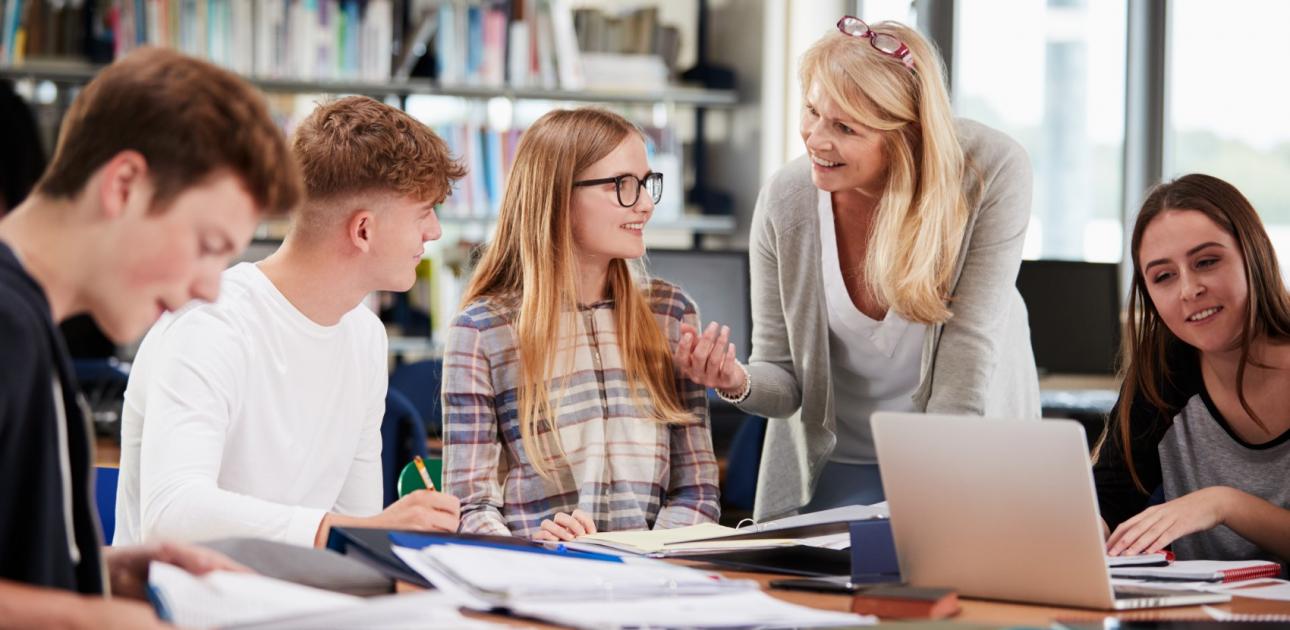 Skolotāja ar skolēniem bibliotēkā