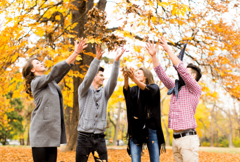 Attēlā redzami priecīgi jaunieši rudens lapās