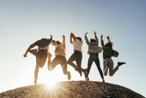 Attēlā redzami jaunieši, kas lec uz akmens