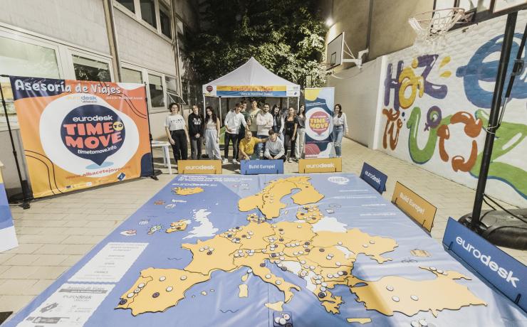 Cilvēku grupa pie lielformāta spēles, kurā attēlota Eiropas karte